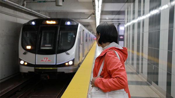 Woman on subway platform watching subway pull in.